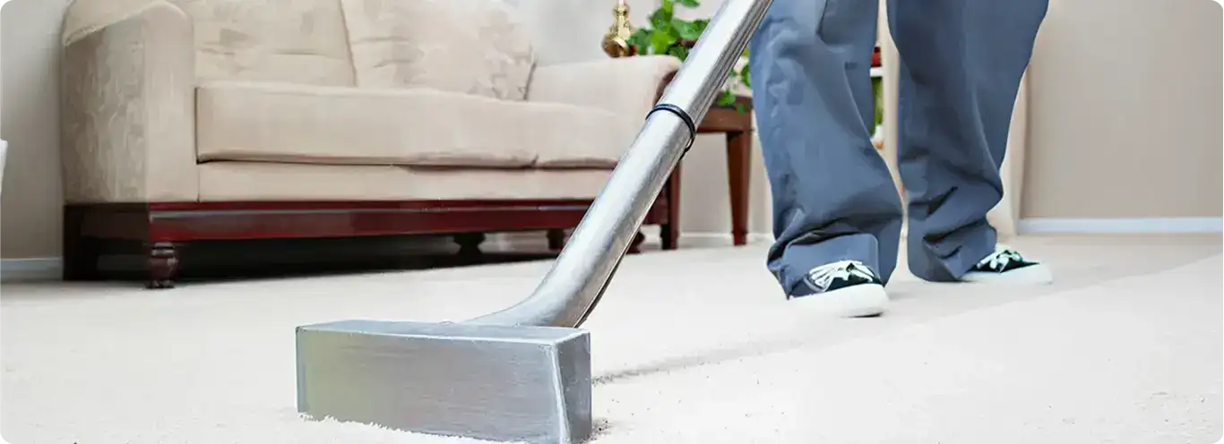 Carpet cleaning technician using a hot-water extraction wand on a light-colored carpet in a living room, Chandler, AZ.