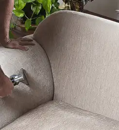 Professional upholstery cleaner deep-cleaning a fabric sofa with a handheld extraction tool and hose Chandler, AZ.